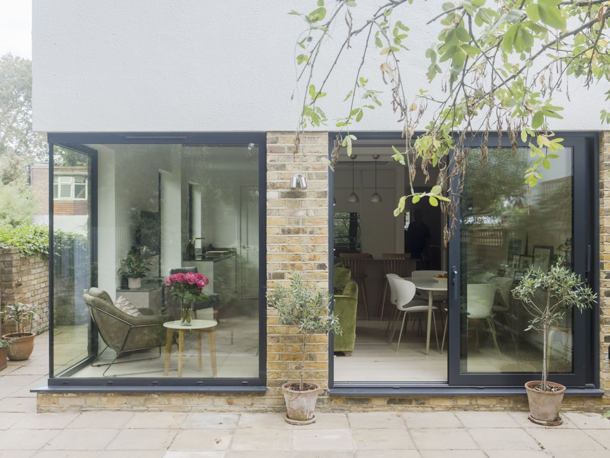 New large glazing aluminium sliding door and corner window with views into the open plan living space. Newly fitted lemon grass kitchen and interior design furniture. Re-exposed brick wall with white render to the first floor..